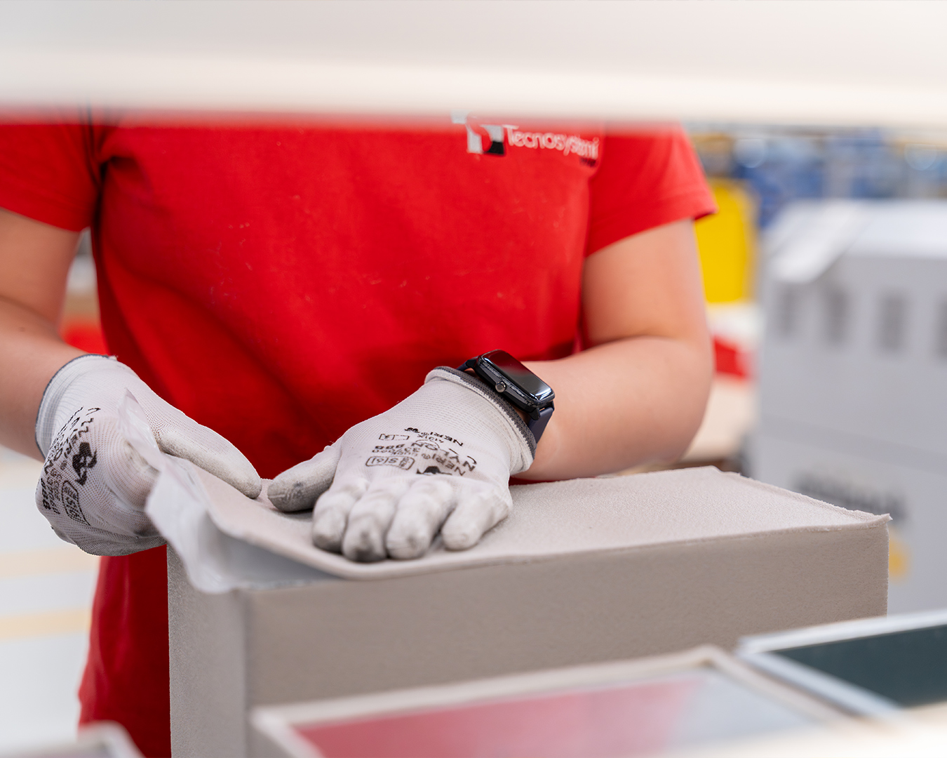 persona in produzione con maglia rossa Tecnosystemi che assembla un plenum di distribuzione per HVAC